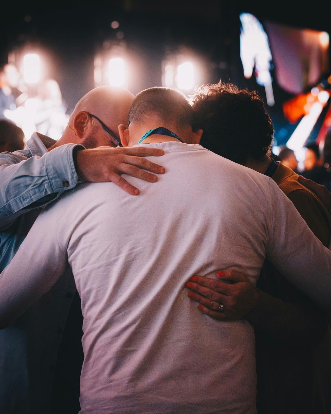 Three people standing close with their arms around one another